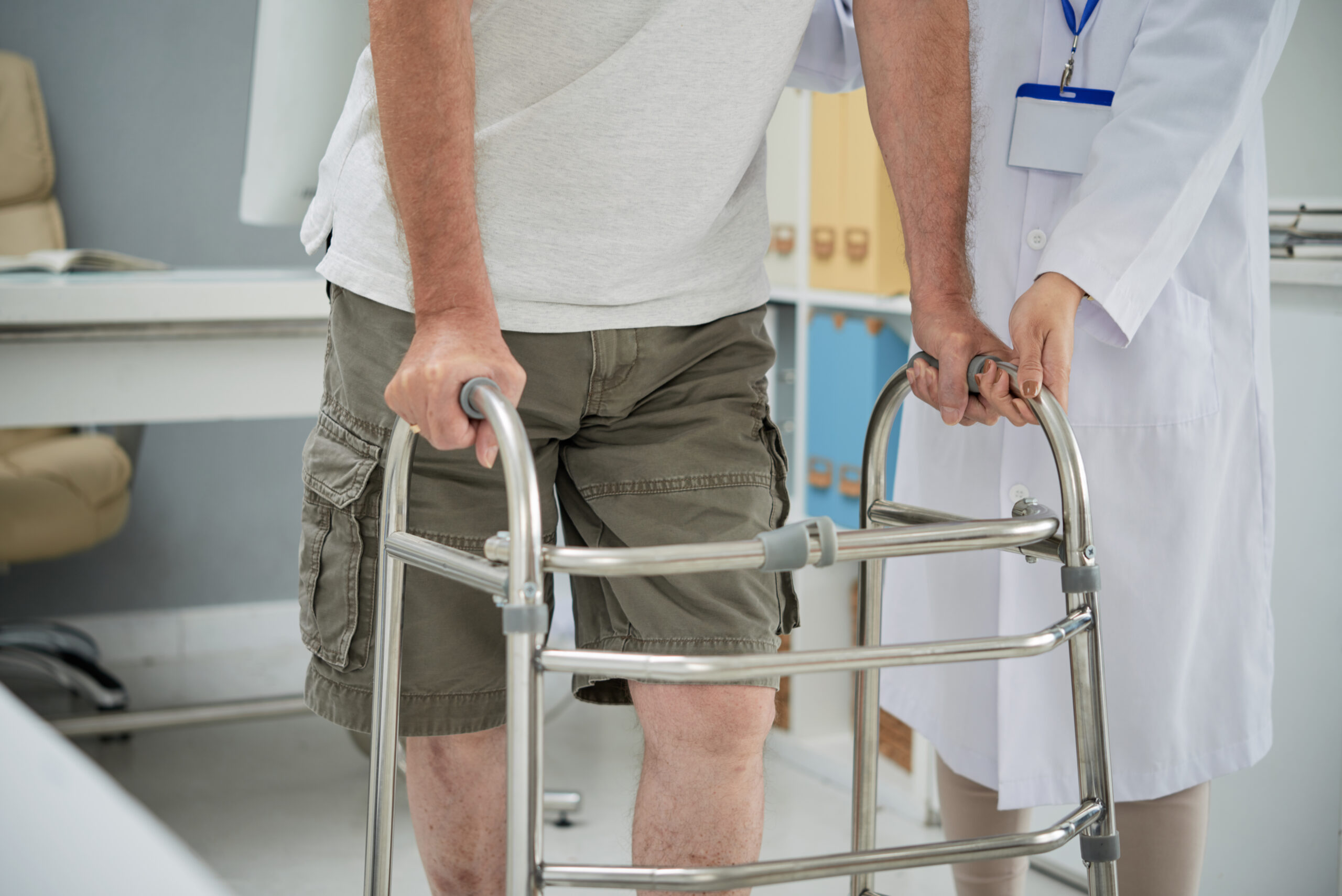 Man making first steps with help of walker after rehabilitation therapy